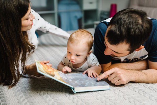 Parents reading book to baby